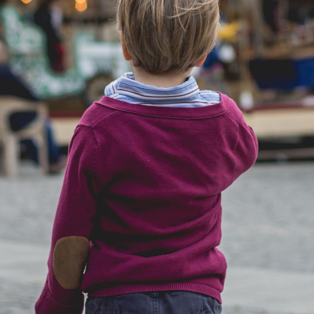 Toddler boy in a burgundy elbow-patch sweater seen from behind at an outdoor market | Bundled gently-loved boy clothing bundles Canada, affordable one of a kind baby boy outfits from newborn to 24 months