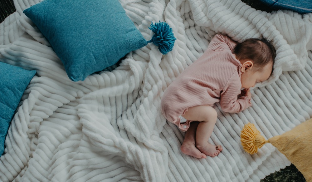Newborn resting on a soft blanket in gently-loved clothing | Bundled sustainable childrenswear, mindful clothing choices for Canadian families