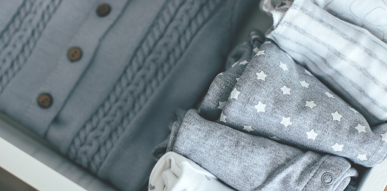 Neatly folded gently-loved baby clothes stacked in soft grey and white | Bundled shop all bundles, curated one of a kind childrenswear newborn to 24 months in Canada