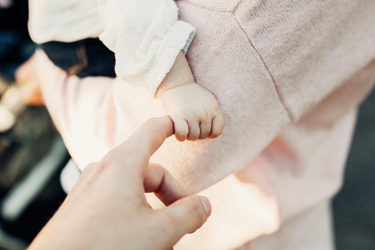 Newborn hand wrapped around a parent's finger | Bundled sustainable childrenswear, giving gently-loved baby clothes a happy second life in Canada